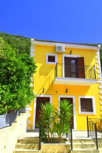a yellow house with palm trees in front of it at Dourios Ippos Apartments in Frikes