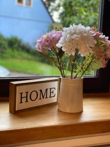 a vase with flowers on a window sill next to a home sign at Ferienwohnung Hopfengarten in Spalt