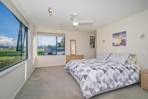 a bedroom with a bed and a large window at Pauanui Hangar Retreat - Pauanui Holiday Home in Pauanui