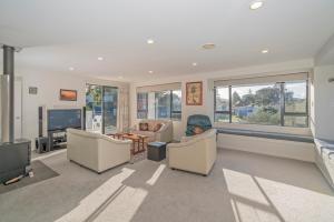 a living room with two chairs and a tv at Pauanui Hangar Retreat - Pauanui Holiday Home in Pauanui