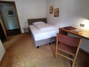 a bedroom with a bed and a desk and a chair at Garni Weghueb in Rablà
