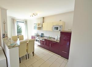 een keuken met paarse kasten en een tafel en stoelen bij Haus Triade Ferienwohnung Triade 4 in Zinnowitz