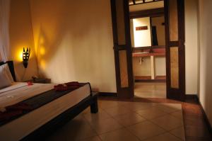 1 dormitorio con 1 cama y 1 habitación con puerta en Tirta Sari Bungalow, en Pemuteran