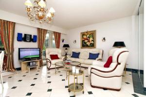 a living room with white furniture and a tv at Riviera Golf de Barbossi Indiana in Mandelieu-la-Napoule
