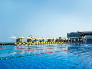 a large swimming pool with yellow chairs and umbrellas at Oceanami Villas & Beach Club 3 bedroom villa in Long Hai