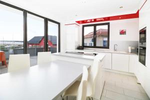 a white kitchen with a long white table and chairs at Ferienwohnung Leuchtfeuer 6 OG in Peenemünde