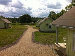 a dirt road next to a field with buildings at Valaste Puhkeküla in Kohtla-Järve