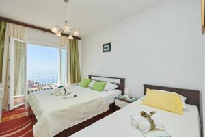 two beds in a room with a view of the ocean at Guest House Medzalin in Dubrovnik