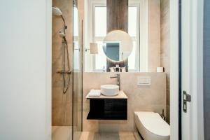 een badkamer met een wastafel, een toilet en een spiegel bij Amsterdam Beach Hotel in Zandvoort