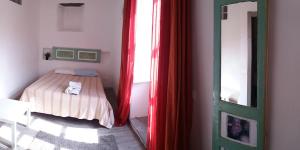 a bedroom with a bed with red curtains and a mirror at Appartamenti del Comandante in Santa Marina Salina