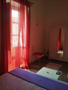 a bedroom with a bed and red curtains and a chair at Appartamenti del Comandante in Santa Marina Salina