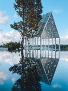 ein Glashaus auf dem Wasser mit einem Baum in der Unterkunft UCSI Hotel Kuching in Kuching