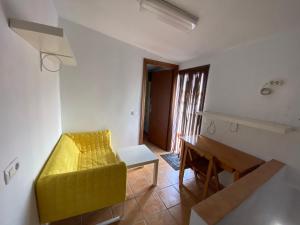 a living room with a yellow couch and a table at APARTAMENTO RURAL CASA MONTE in Cazalla de la Sierra