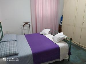 ein Bett mit einer lila Decke und Kissen darauf in der Unterkunft IGGH Il Glicine Guest House in San Benedetto del Tronto