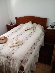 a bed with a white comforter with shoes on it at Casal do Avô Francisco in Caldas da Rainha