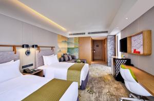 広州市にあるHoliday Inn Guangzhou South Lake, an IHG Hotelのベッド2台とテレビが備わるホテルルームです。