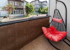 huśtawka na ganku z czerwonym siedzeniem przed oknem w obiekcie Mieszkanie Next - ACCO RENT w mieście Sopot +4 zdjęcia