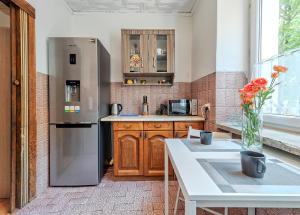 a kitchen with a refrigerator and a table with a vase of flowers at Mieszkanie Next - NoclegiSopot in Sopot