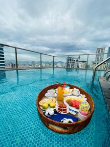 a tray of food on the edge of a swimming pool at Sofiana My Khe Hotel & Spa- Rooftop Pool Bar in Danang