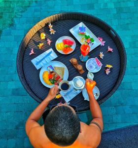a man is sitting at a table with food at Sofiana My Khe Hotel & Spa- Rooftop Pool Bar in Danang