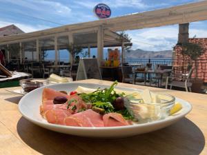 a plate of food on a table with a salad at Apartments Baška in Baška
