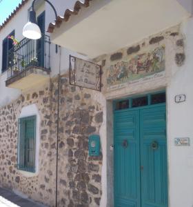 a building with a blue door and a sign on it at B&B Sa domo de sos Massaios in Orosei