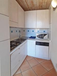 een keuken met witte kasten, een wastafel en een fornuis bij Appartamento elegante a Marina di Campo in Campo nell'Elba