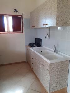 uma cozinha branca com um lavatório e uma janela em Faraglioni house em Favignana