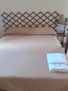 un letto con una coperta bianca e due asciugamani sopra di Faraglioni house a Favignana