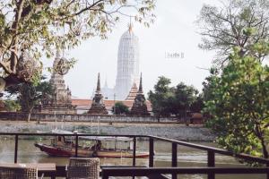 a boat on the river in front of a temple at iuDia Hotel in Phra Nakhon Si Ayutthaya