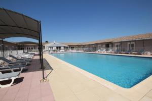 a large swimming pool with lounge chairs and umbrellas at Hôtel Saint Louis in Le Thor