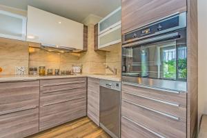 a kitchen with wooden cabinets and stainless steel appliances at Victus Apartamenty, Victus Apartament Meru in Sopot