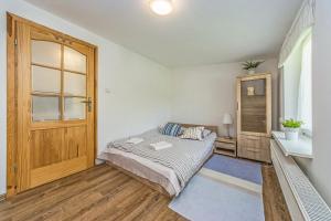 a bedroom with a bed and a wooden door at Victus Apartamenty, Victus Apartament Meru in Sopot