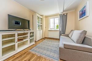 a living room with a couch and a tv at Victus Apartamenty, Victus Apartament Meru in Sopot
