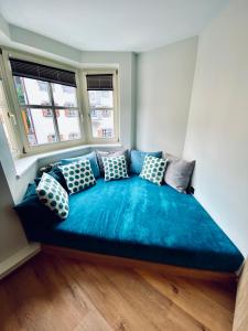 a large blue bed in a room with two windows at Roomie Alps Design Hostel in Kitzbühel