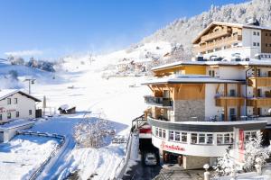 a building in the snow next to a mountain at Hotel Sonnleiten in Ladis