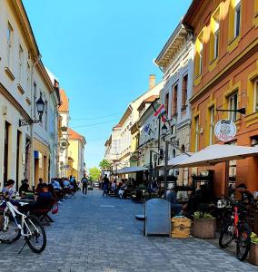 a city street with people sitting at tables and buildings at Malasits Apartman in Győr
