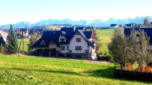 a house in a field with mountains in the background at Willa Galówka in Szaflary