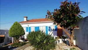 une maison bleue et blanche avec des arbres devant elle dans l'établissement Casa de Praia, à Vila do Conde