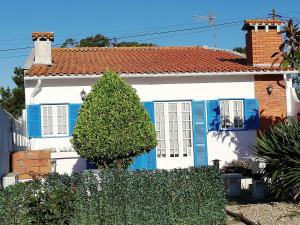 Casa de Praia في فيلا دو كوندي: بيت أبيض وبه مصاريع زرقاء وشجرة