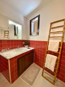 La salle de bains en carrelage rouge est pourvue d'un lavabo et d'une échelle. dans l'établissement La depandance di Villa Rosa locazioni brevi, à Mondello