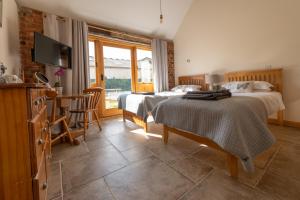 1 dormitorio con 2 camas, mesa y TV en Mill Cottage - Ash Farm Cotswolds en Stow on the Wold