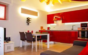 a kitchen with red cabinets and a table and chairs at Holiday House Viola in Tirano