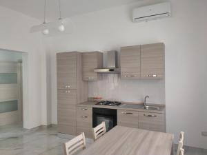 uma cozinha com armários de madeira e uma mesa com cadeiras em Casa Vacanze Vega em Porto Cesareo