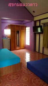 2 camas en una habitación con paredes moradas y cocina en สุขกมลรับอรุณแฝด2ห้อง en Chanthaburi