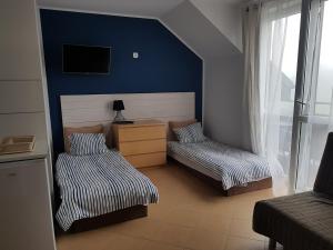 a bedroom with two beds and a blue wall at Wysoka Fala in Jastrzębia Góra