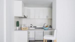 a white kitchen with white cabinets and a sink at Cornisa Apartments in Patalavaca