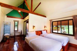 Un dormitorio con dos camas y una ventana. en Phayamas Private Beach Resort and Island Brew - Adults Only, en Ko Phayam