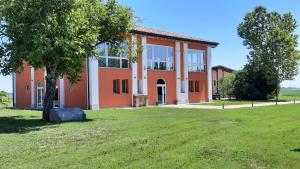 un grand bâtiment orange avec un arbre en face dans l'établissement Agriturismo Al Navile, à Malalbergo