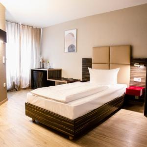 a bedroom with a large bed and a desk at Arkade Hotel am Theater in Heilbronn